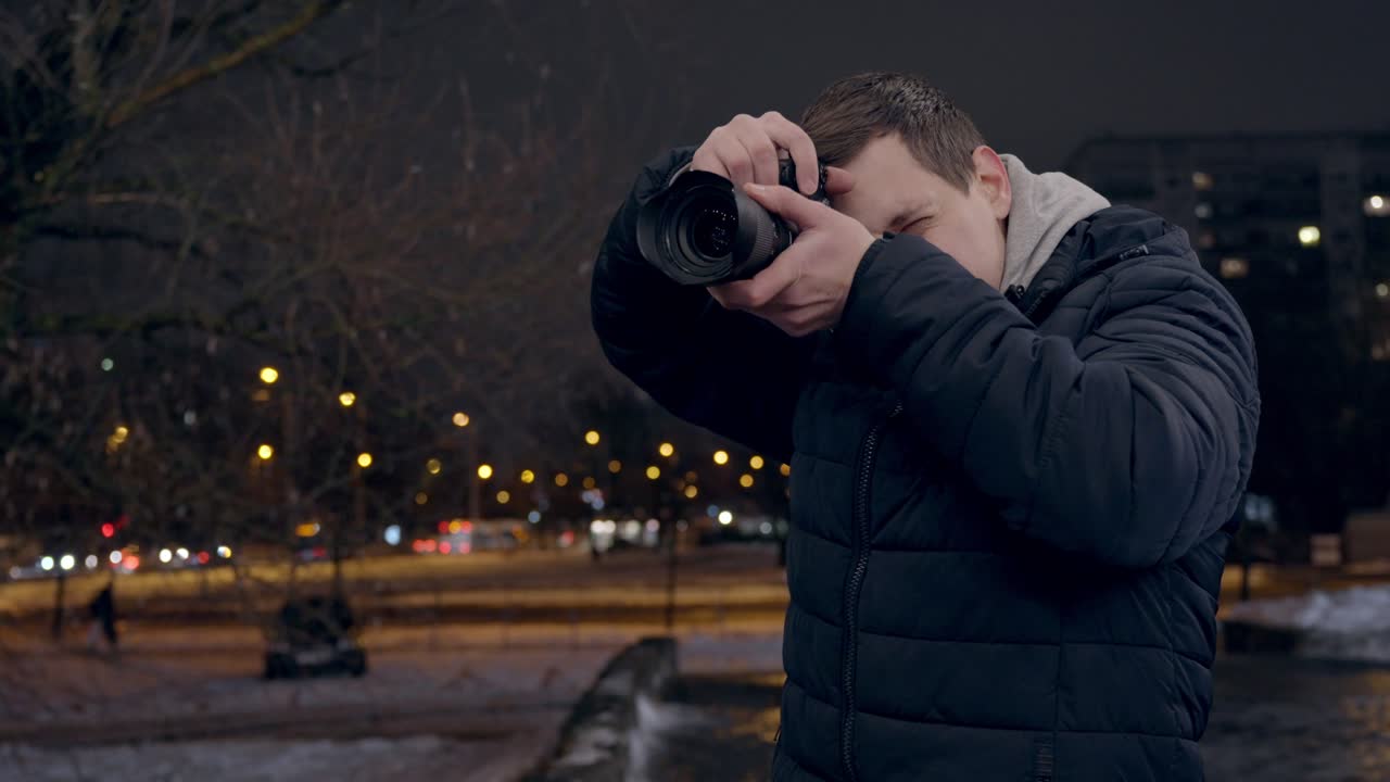 Giovane turista scatta foto di notte in città, guarda l'immagine e sorride.