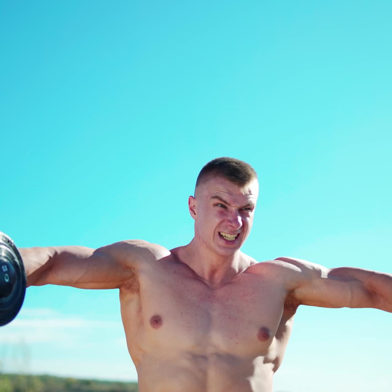 . Workout fitness sport. Concentrated young sportsman outdoors exercising for upper arms with dumbbells