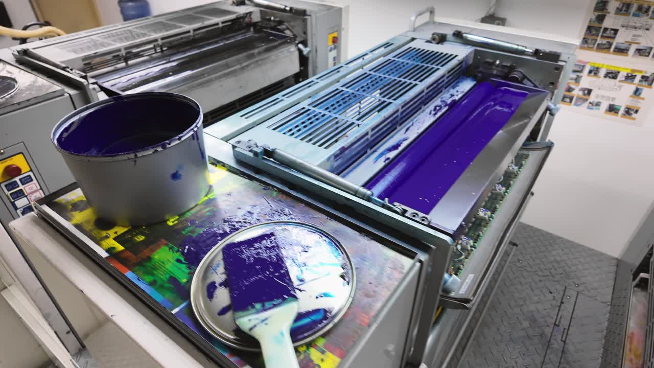 Black, cyan, and magenta ink tins sit atop the lithographic offset printing units, ready for use in the color printing process