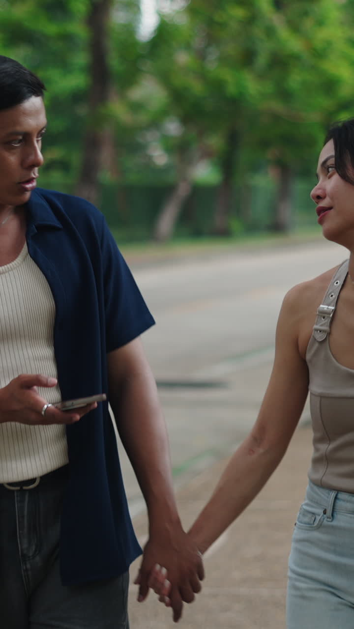 Couple holding hands and looking at a phone outdoors