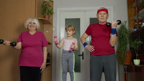 Active-senior-couple-grandmother-grandfather-with-child-kid-girl-doing-fitness-dumbbells-exercises