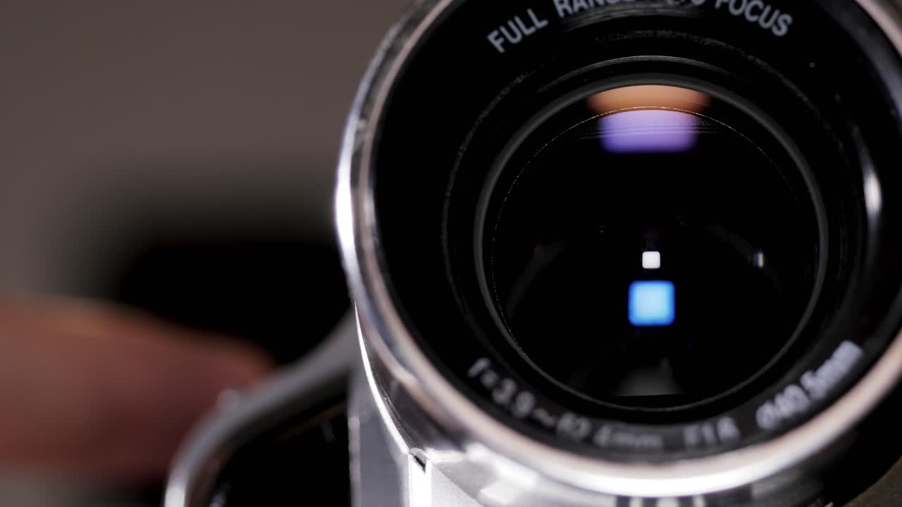 Close up of a silver camcorder lens tightening into sharp focus, ideal for filmmaking and tech visuals