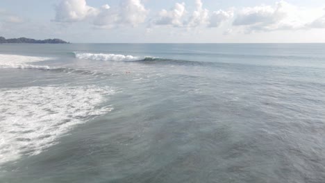 Luftaufnahme-Von-Menschen,-Die-Auf-Einem-Surfbrett-Am-Dominanten-Strand-Schwimmen,-Weitwinkelaufnahme