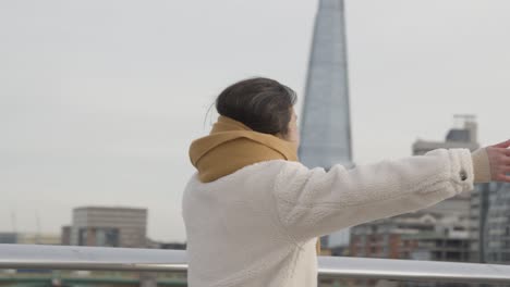 young asian couple meeting and hugging on millennium bridge in london uk 1