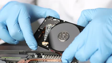 hands in blue gloves handling an open hard drive
