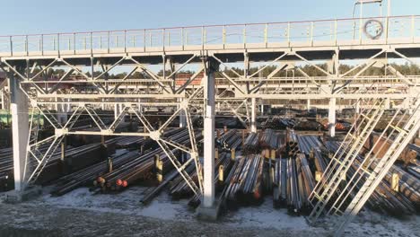 drone view of round metal pipes in metal warehouse with railway access.