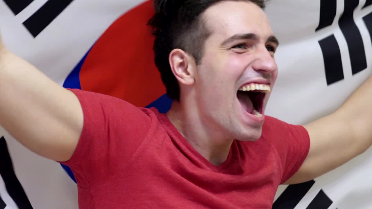 느린 동작으로 한국의 발을 들고 축하하는 한국 젊은이