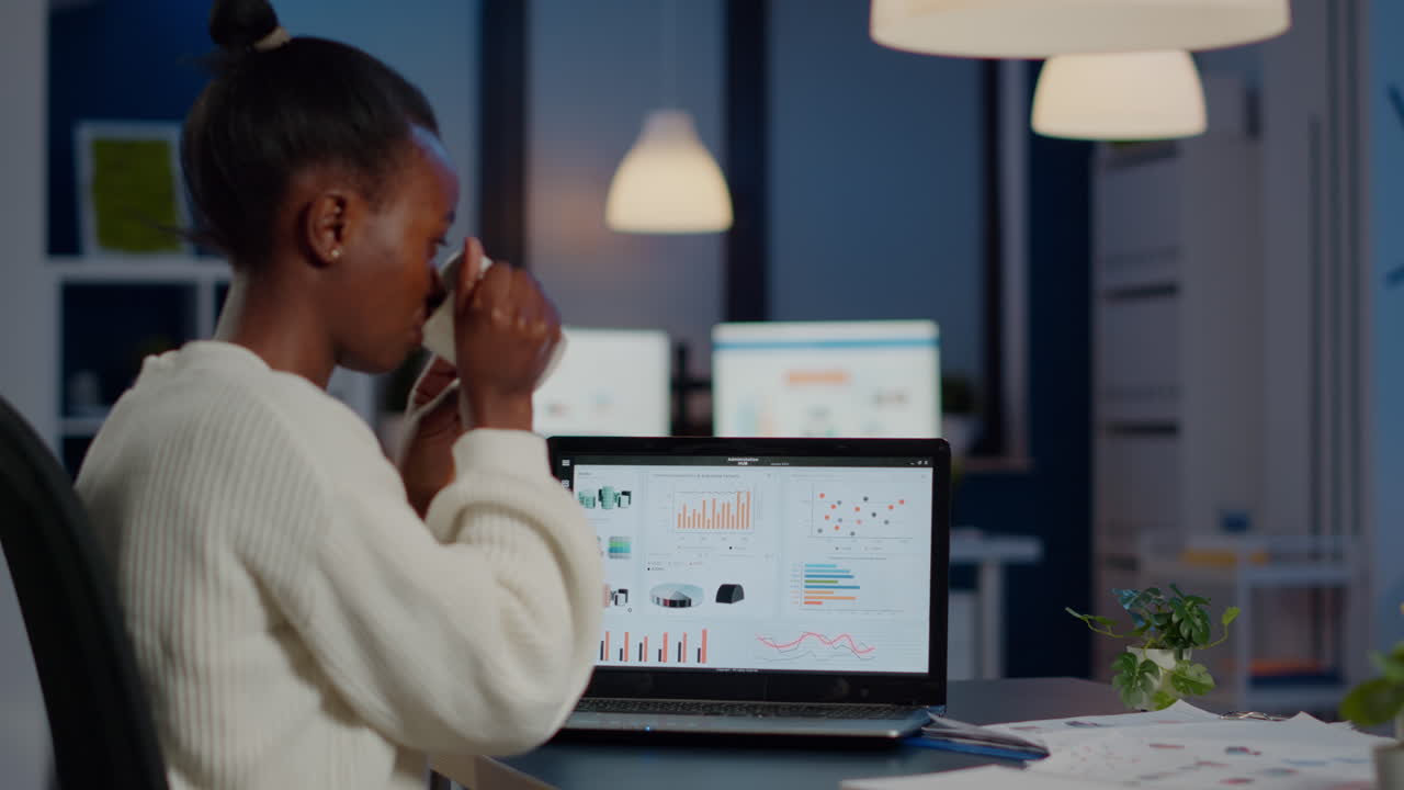 Black manager checking business statistics and financial reports on laptop