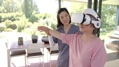 using vr headset, senior asian woman doing physical therapy with therapist at home