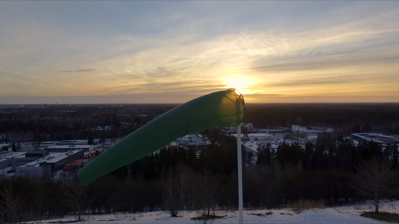 백그라운드에서 천천히 떠오르는 태양과 함께 상쾌한 이른 아침에 바람이 부는 바람막이의 공중 샷을 닫습니다.