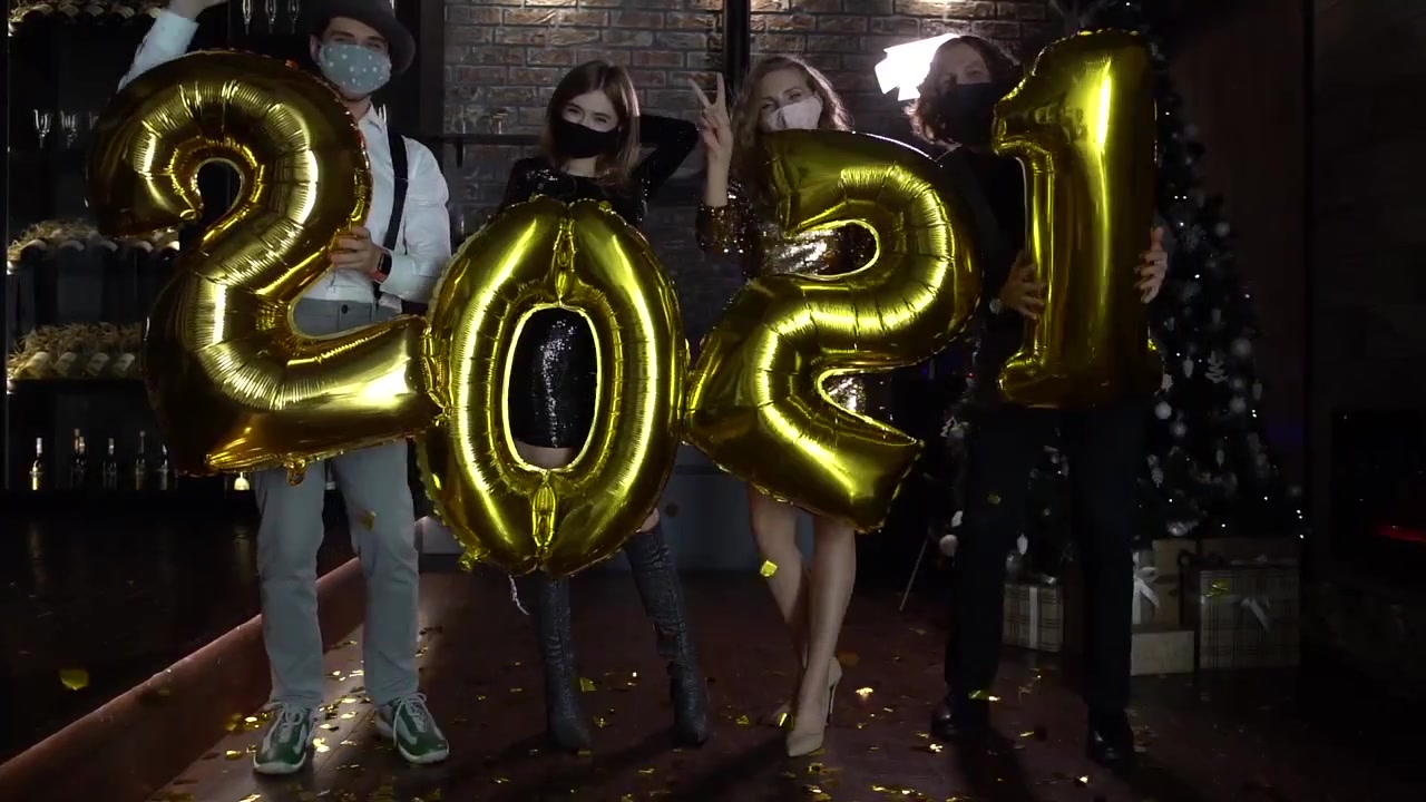 Gruppo di amici che festeggia il Capodanno con palloncini dorati "2021"