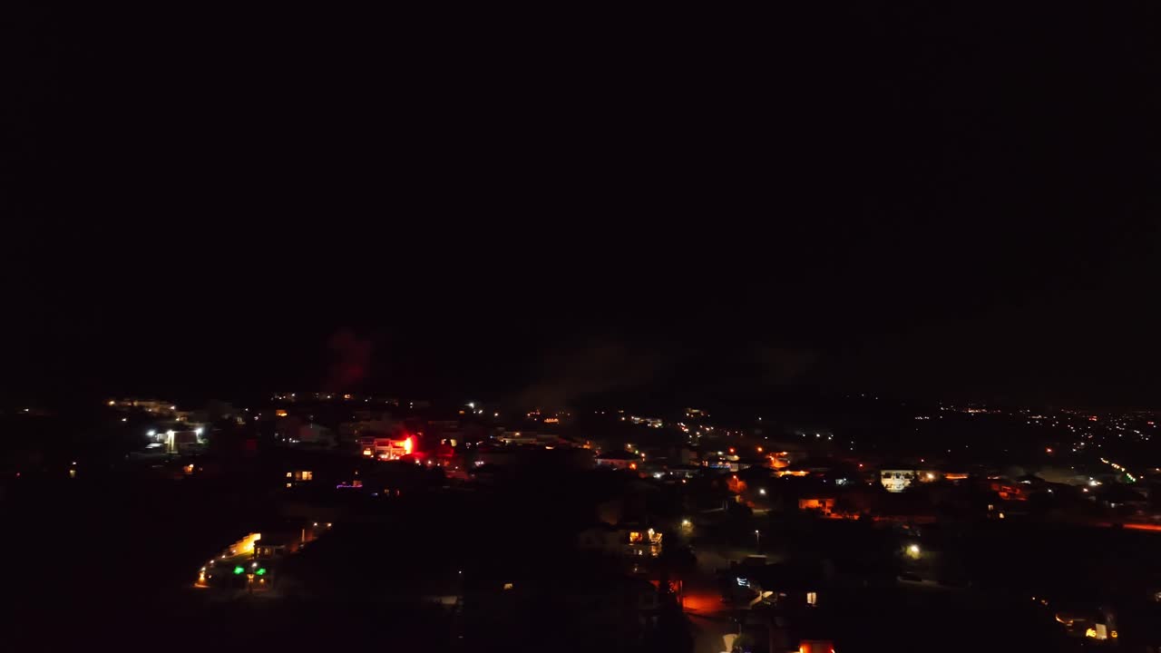 New Year's Eve fireworks over brightly lit city skyline, night celebration, vibrant bursts, and festive ambiance.