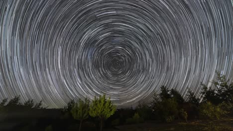 the stars moving around the night sky keeping it trails as it turn around the celestial equator. an amazing starry night view to see the earth rotation movement in the sky at an idyllic landscape