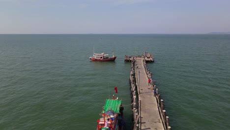 Imágenes-Aéreas-Hacia-El-Final-Del-Muelle-De-Pesca-De-Pattaya-Revelando-Tres-Barcos-De-Pesca-Y-El-Muelle-A-La-Derecha,-Pattaya,-Tailandia