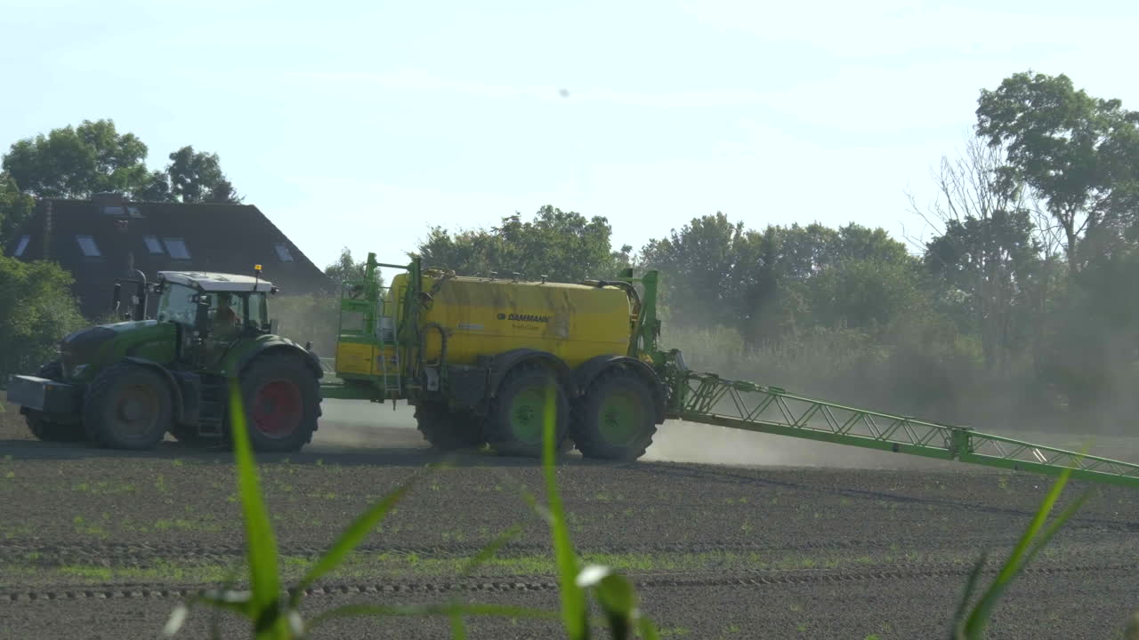 Agricoltore che irrora i campi con trattore e irroratrice