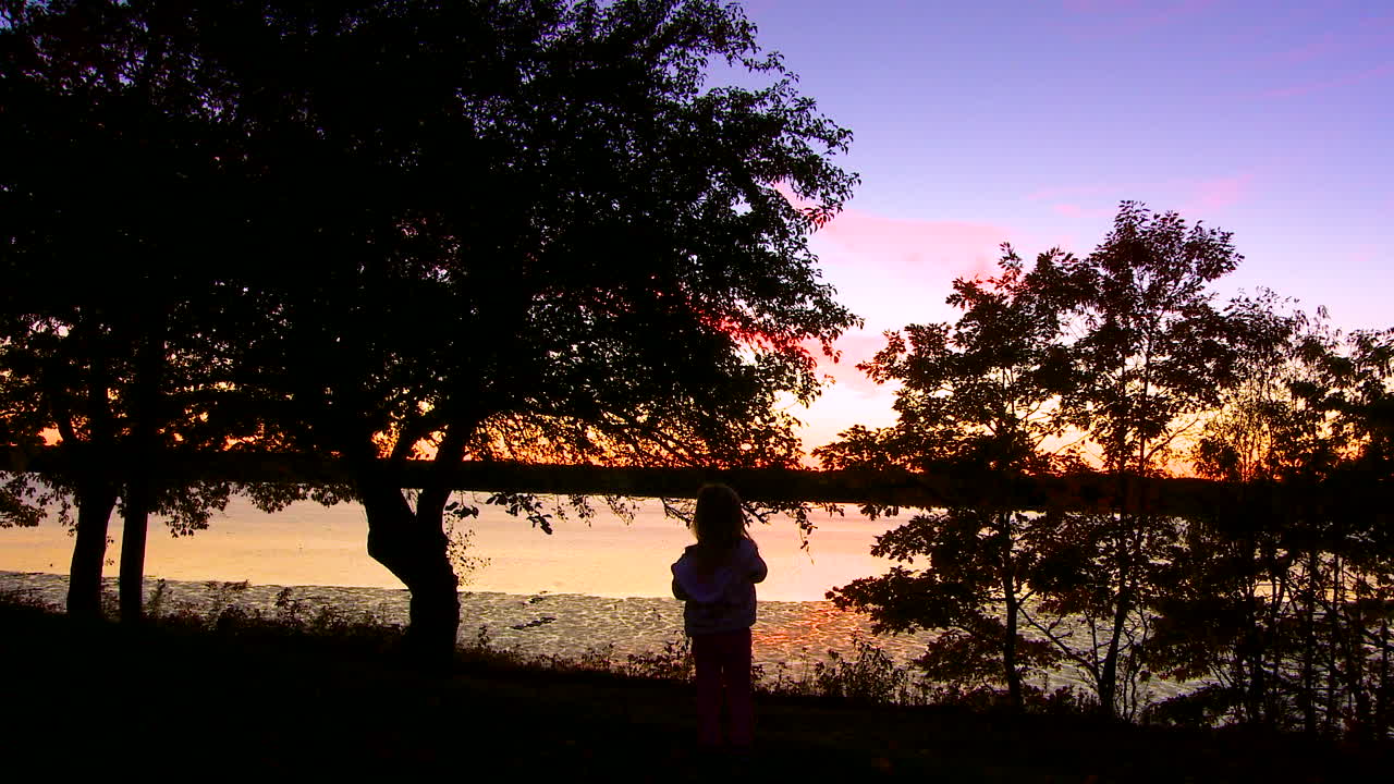 한 사람이 황혼에 아름다운 호수 앞에 서 있다