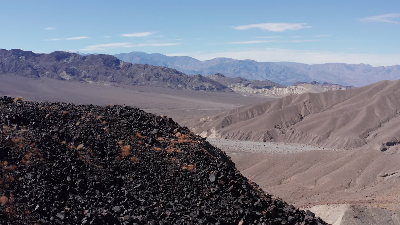 Aerial close-up shot flying over a rocky ridge towards Death Valley National Park, California. 4K