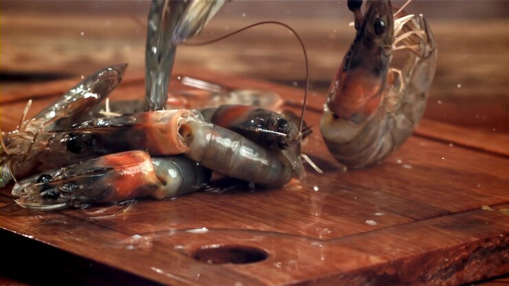 Fresh Raw Shrimp Falling onto a Wooden Cutting Board in Slow Motion