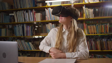 chica adolescente usando una computadora portátil y gafas de realidad virtual en la biblioteca, de mano