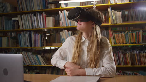 teen girl using a laptop and virtual reality glasses in the library, handheld