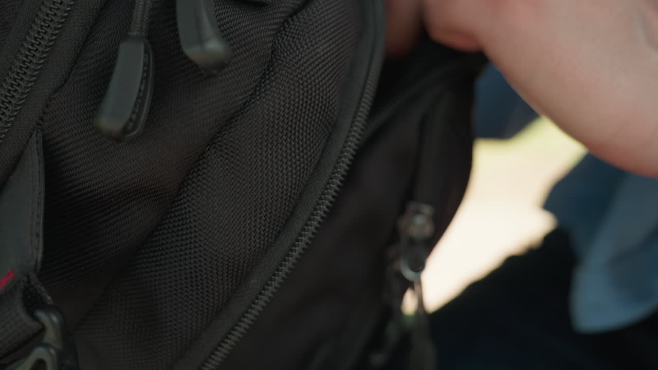 여성이 가방을 찾고 있습니다. 공원에 있는 여성이 백팩 주머니에서 여러 물건을 조심스럽게 찾고 있습니다. 백인 여성이 자연 햇빛을 이용하여 공원 환경에서 백팩 주머니를 주의 깊게 살펴보고 있습니다.