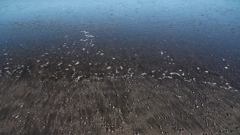 calm water flowing off a black sand beach in iceland on a cold and sunny day in the land of fire and ice