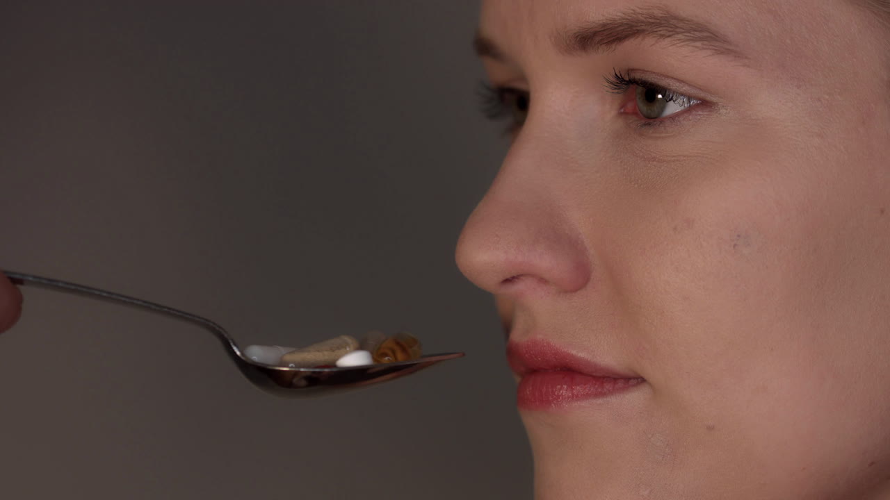 Eating tablets. A young woman puts a spoonful of pills in her mouth. Dietary supplements, vitamins and pain pills