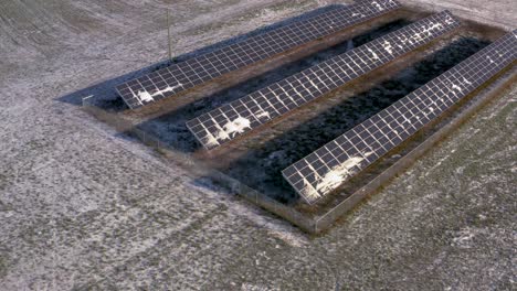 aerial drone view of a lightly snow covered solar panel station powering a farm