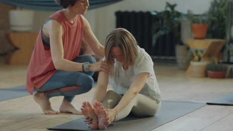 yoga teacher helping women during practice