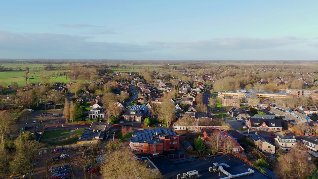 Dronebeelden die in de winter naar rechts bewegen over een dorp en omliggend bos in Eelde, Nederland, waarbij huizen, bomen en het stille landschap zonder sneeuw worden vastgelegd