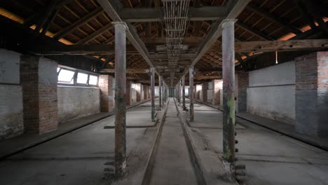 flying-through-an-old-abandoned-empty-livestock-house,-one-point-perspective