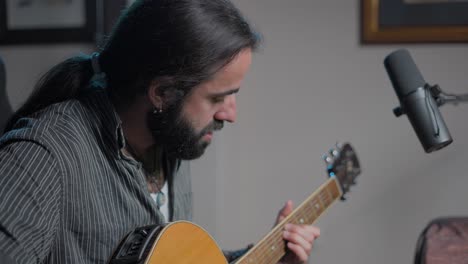 hombre tocando la guitarra acústica en el estudio casero