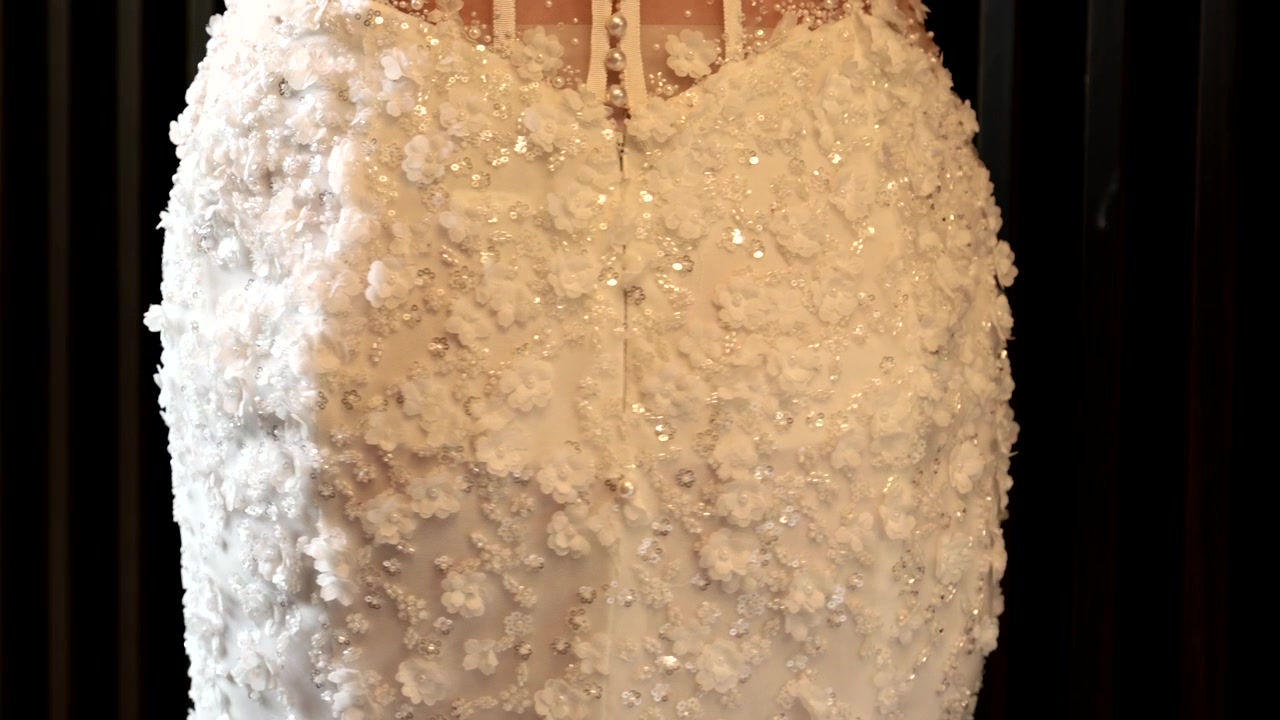 Primo piano dettagliato di tessuto di abito da sposa bianco impreziosito con perle e paillettes