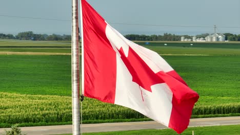 canadian flag waving in front of agricultural landscape