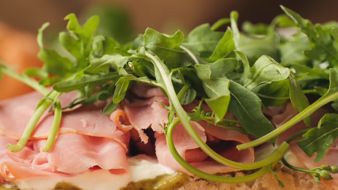 Mortadella ham sandwich, Traditional italian focaccia filled with thin pesto slices of mortadella, served by chef man in cafe restaurant. Macro of traditional italian spanish tapas antipasti.