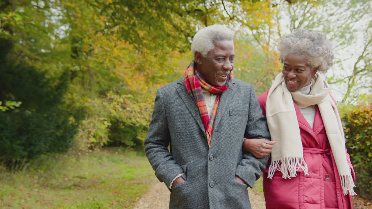 Loving senior couple walking arm in arm through autumn countryside together - shot in slow motion