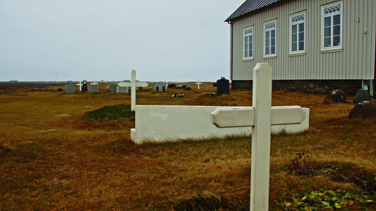 vista portátil de un pequeño y desolado cementerio con crucifijos de madera en tumbas anchas
