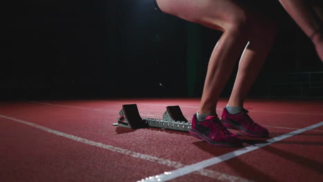 female hispanic athlete training at running track in the dark. slow motion