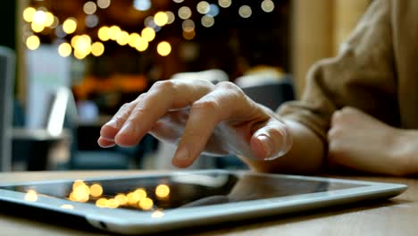 woman uses a tablet computer pc on a blurry background in cafe, close-up