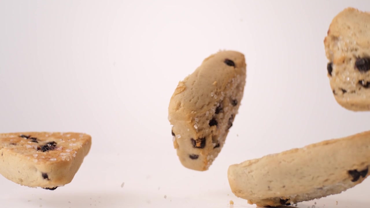 Crumbly fruit-studded scones bouncing and tumbling on white in slow motion macro studio shot. afternoon tea content, british bakery branding, cafe pastry case reels.