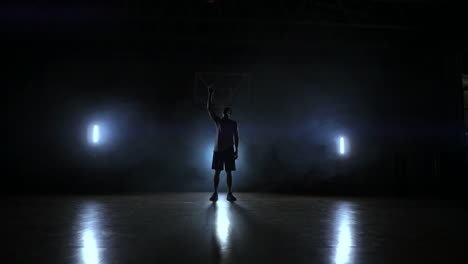 skill dribbling basketball player in the dark on the basketball court with backlit back in the smoke. slow motion streetball