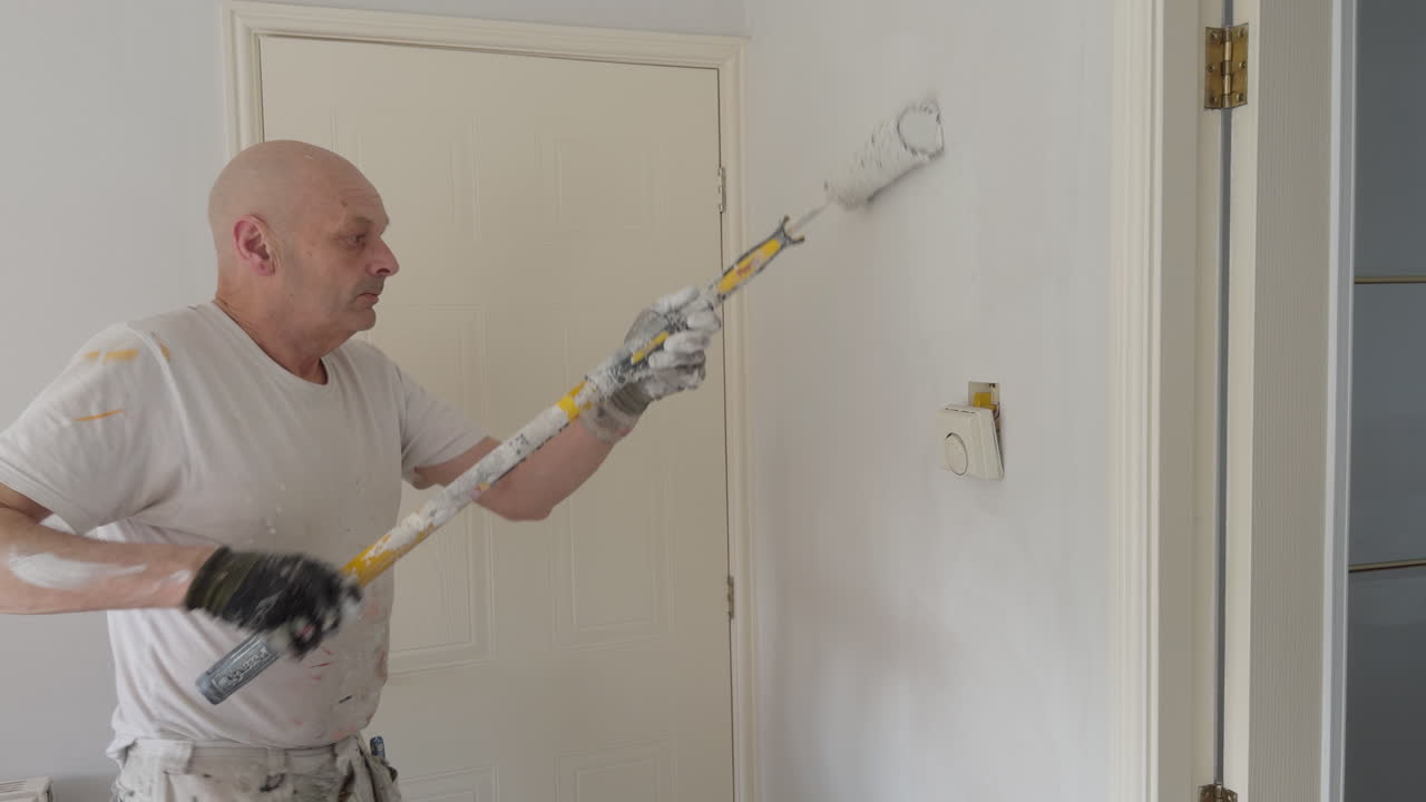 A skilled painter and decorator brings new life to an interior space with fresh white paint and careful technique.