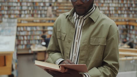 black man reading book in library