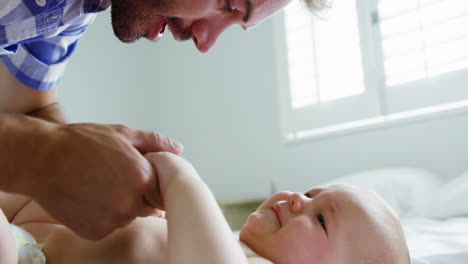 father playing with his baby lying on a bed