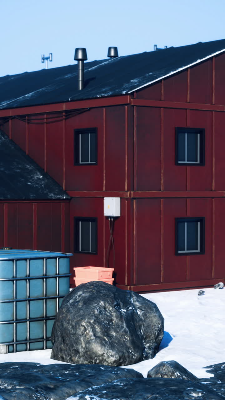 Forskningsbygning i et arktisk landskap omgitt av snø og steiner