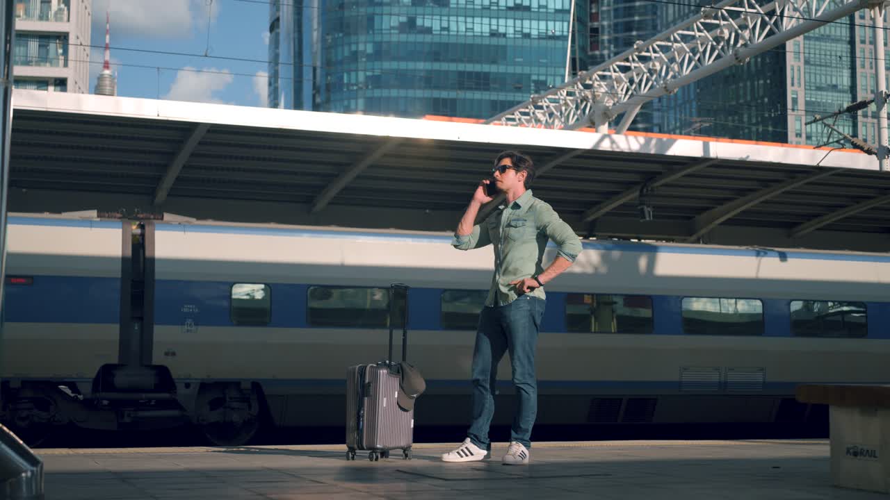 Man Traveler Making a Phone Call At Platform of Seoul Train Station While Waiting By Railroad - slow motion