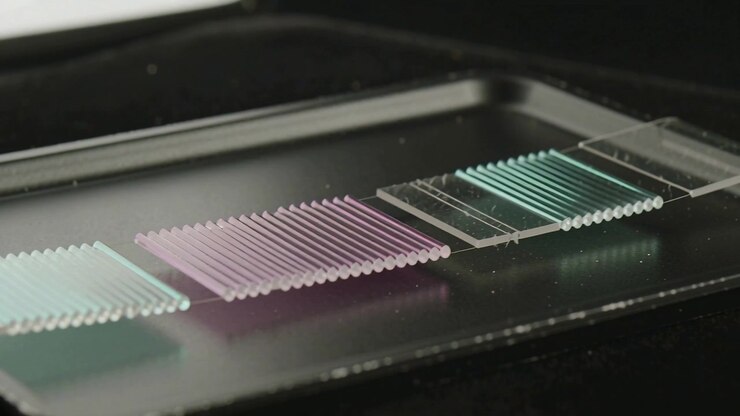 Shifting camera revealing glass slide with cyan magenta ridged arrays on lab bench, showing colors