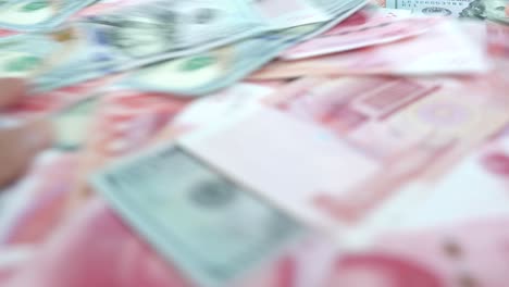 Chinese-and-American-paper-money,-close-up-hands-stirs-shuffles-cash-money-on-the-table,-concept-idea-and-blur-view