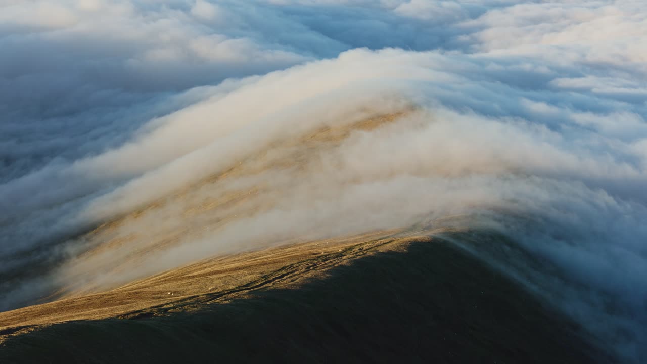 Flowing river of clouds during a temperature inversion over Brecon Beacons at dusk