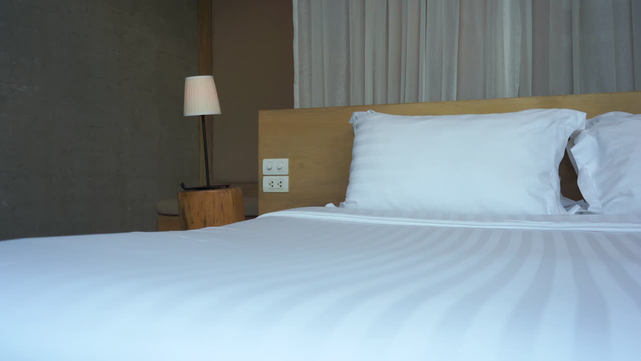 가벼운 산들바람이 화장한 리조트 침대 뒤의 창문 가위를 바스락거립니다.